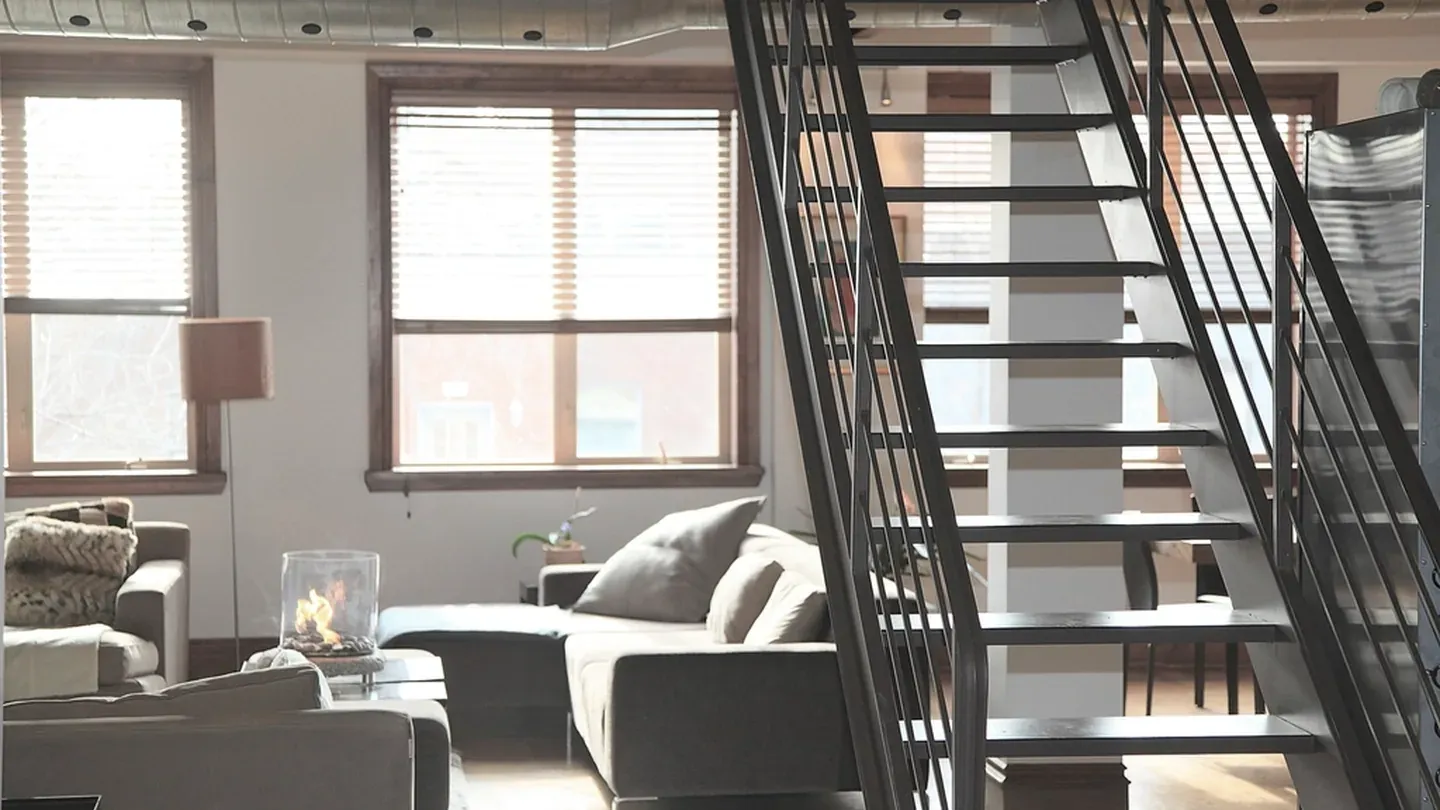 Intérieur de loft industriel: escalier en acier noirci et structure laissée apparente